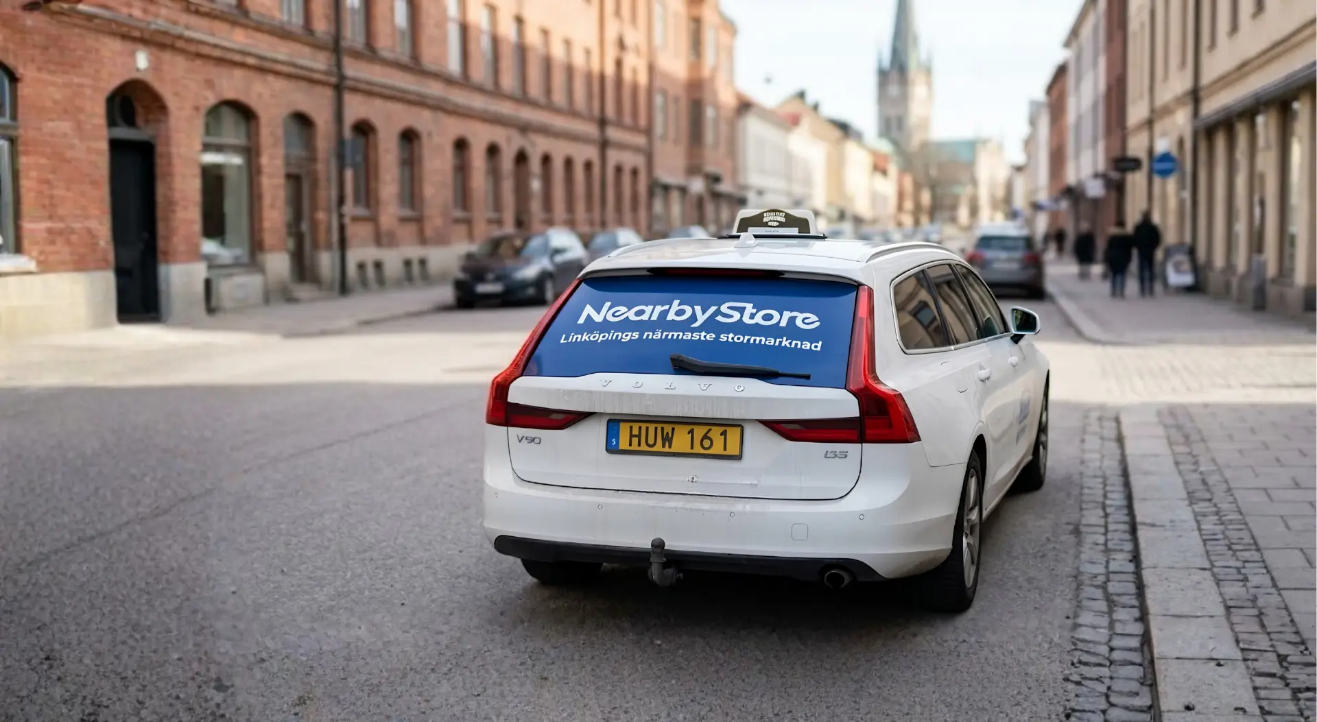 Taxi med bakrutereklam i rörelse på gata i Linköping